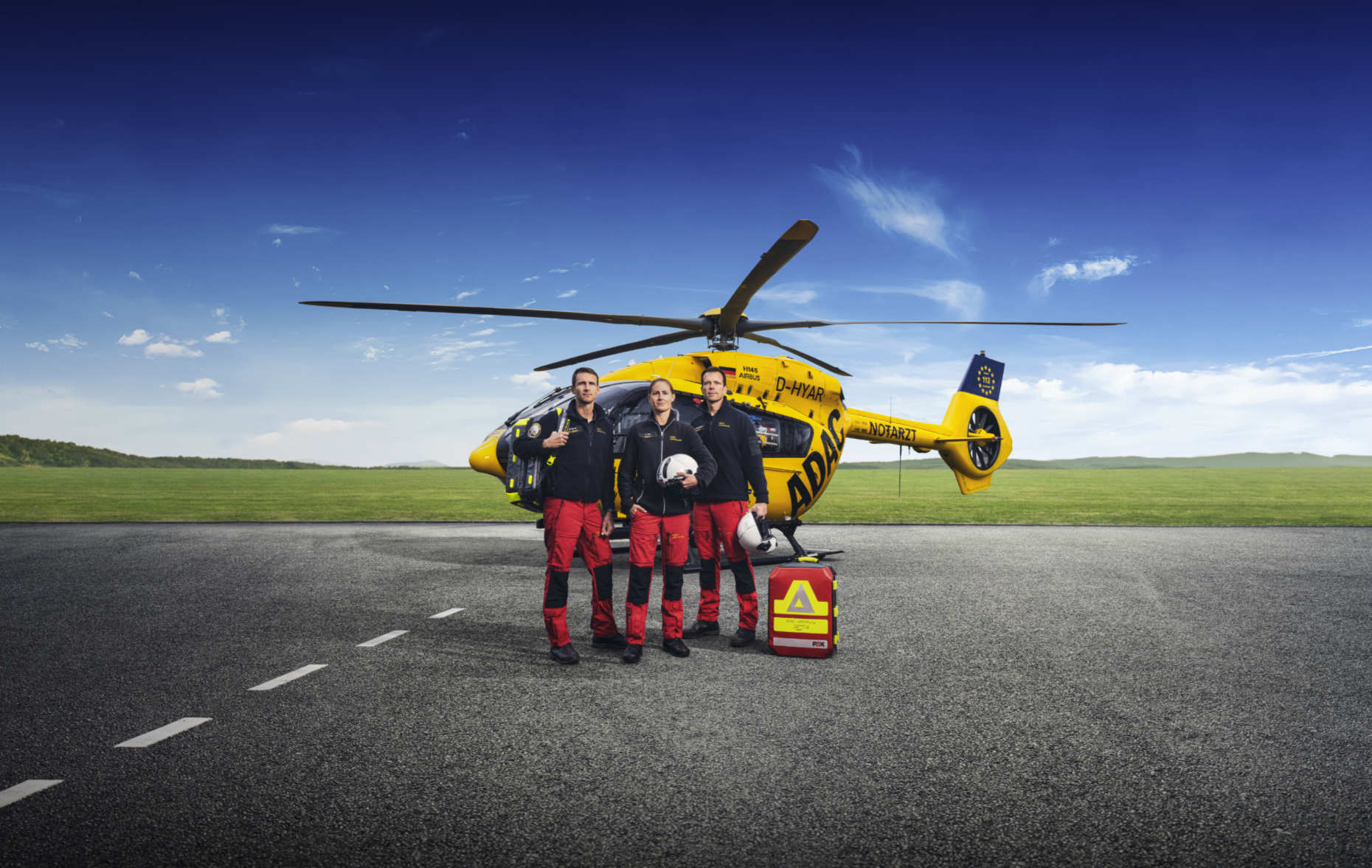 ADAC Luftrettung Mannschaft bestehend aus Pilotin, Arzt und Rettungssanitäter stehen in heroischer Pose vor dem  Christoph H145 Hubschrauber
