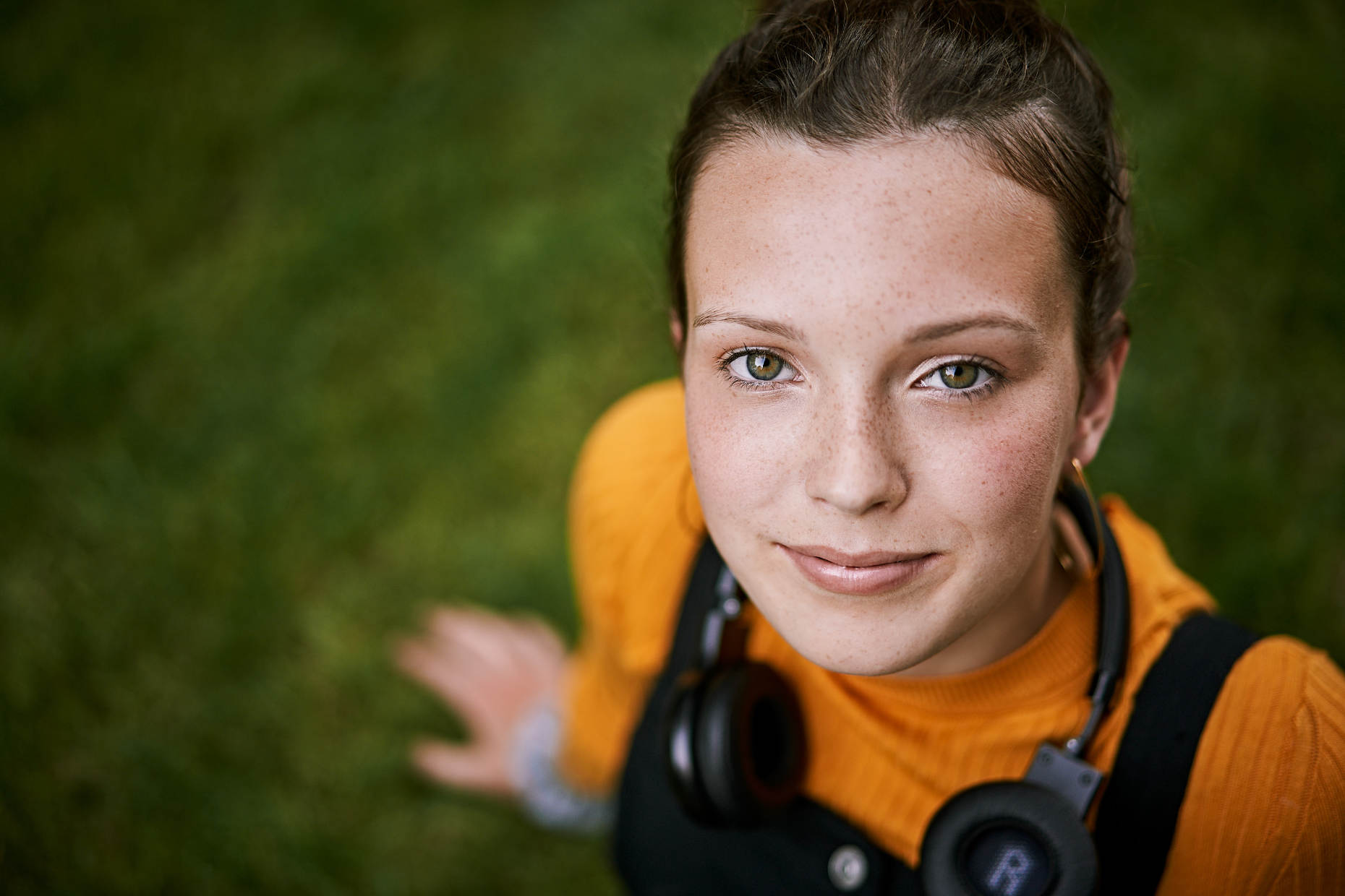 Young girl with freckles wearing head phones around her neck with a very optimistic  and self confident look on her face