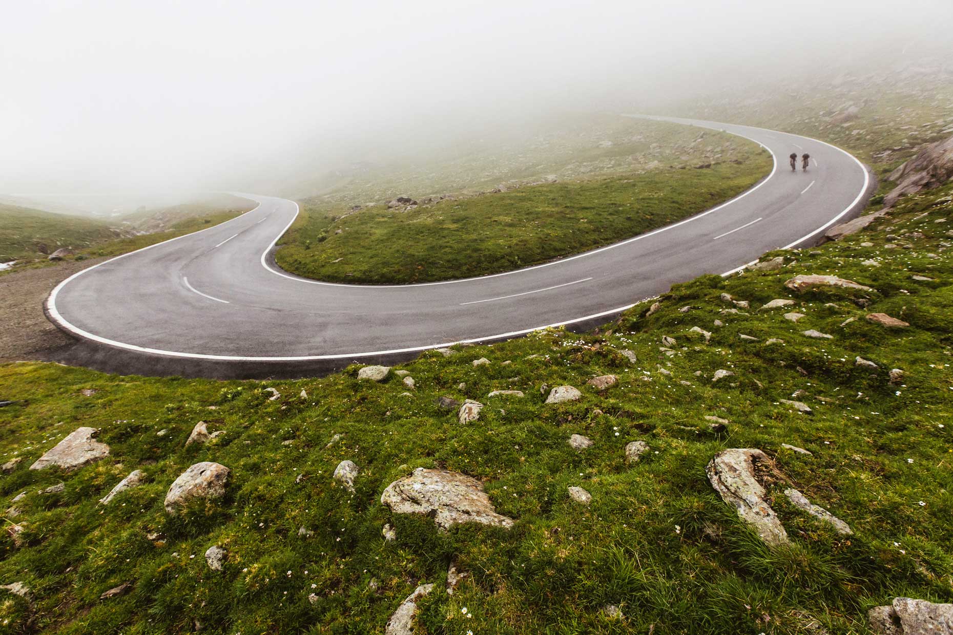A single road cyclist riding downhill in foggy weather on the Timmelsjoch alpine road 